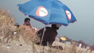 Парень на пляже подсматривает за обнаженными нудистами