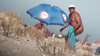 Парень на пляже подсматривает за обнаженными нудистами